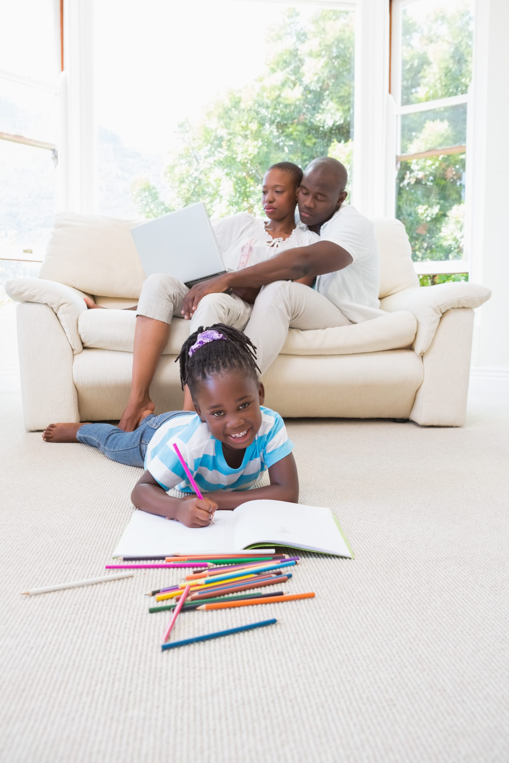 Parents planning on a laptop while their daughter draws